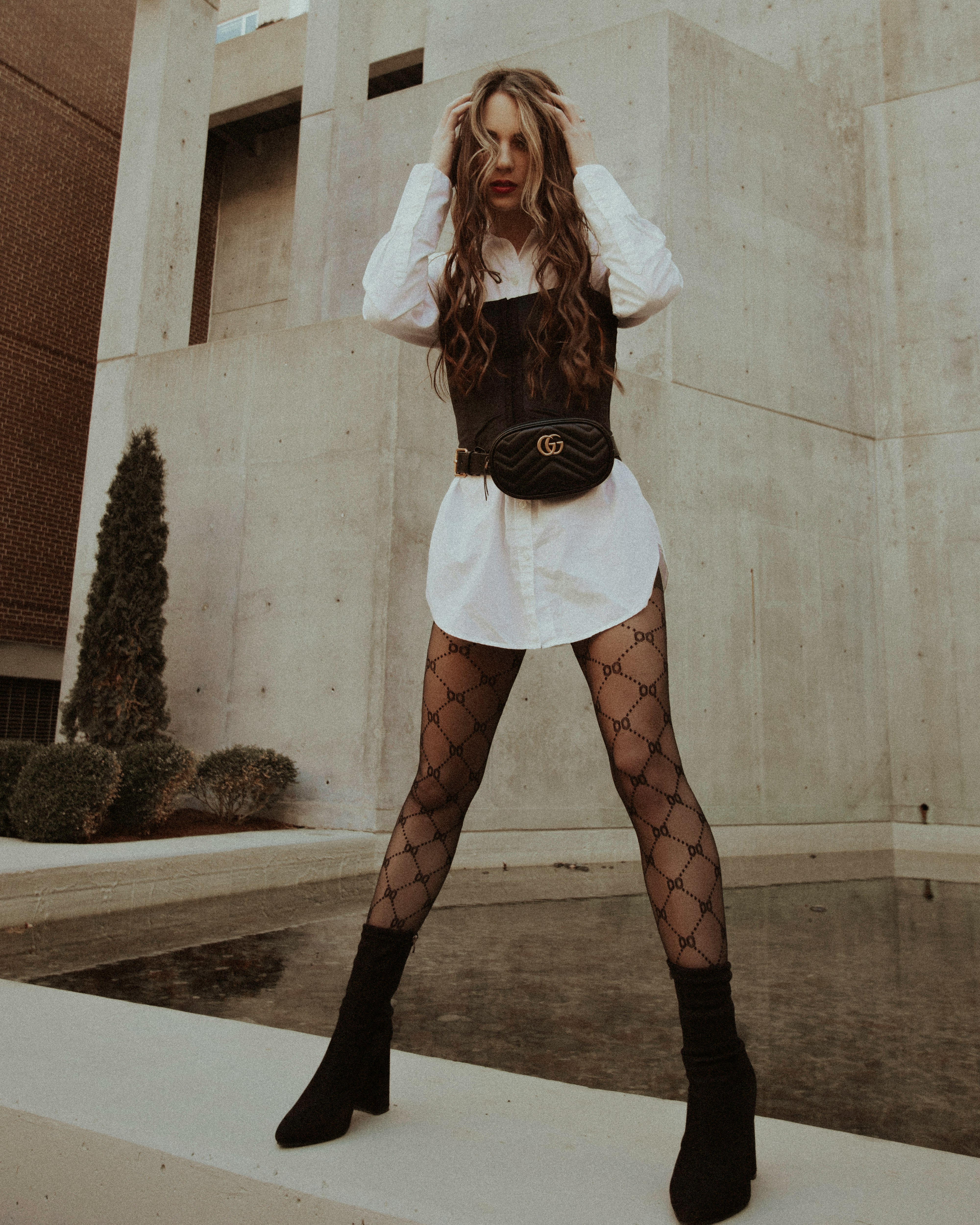 woman in black long sleeve shirt and white skirt standing beside white wall